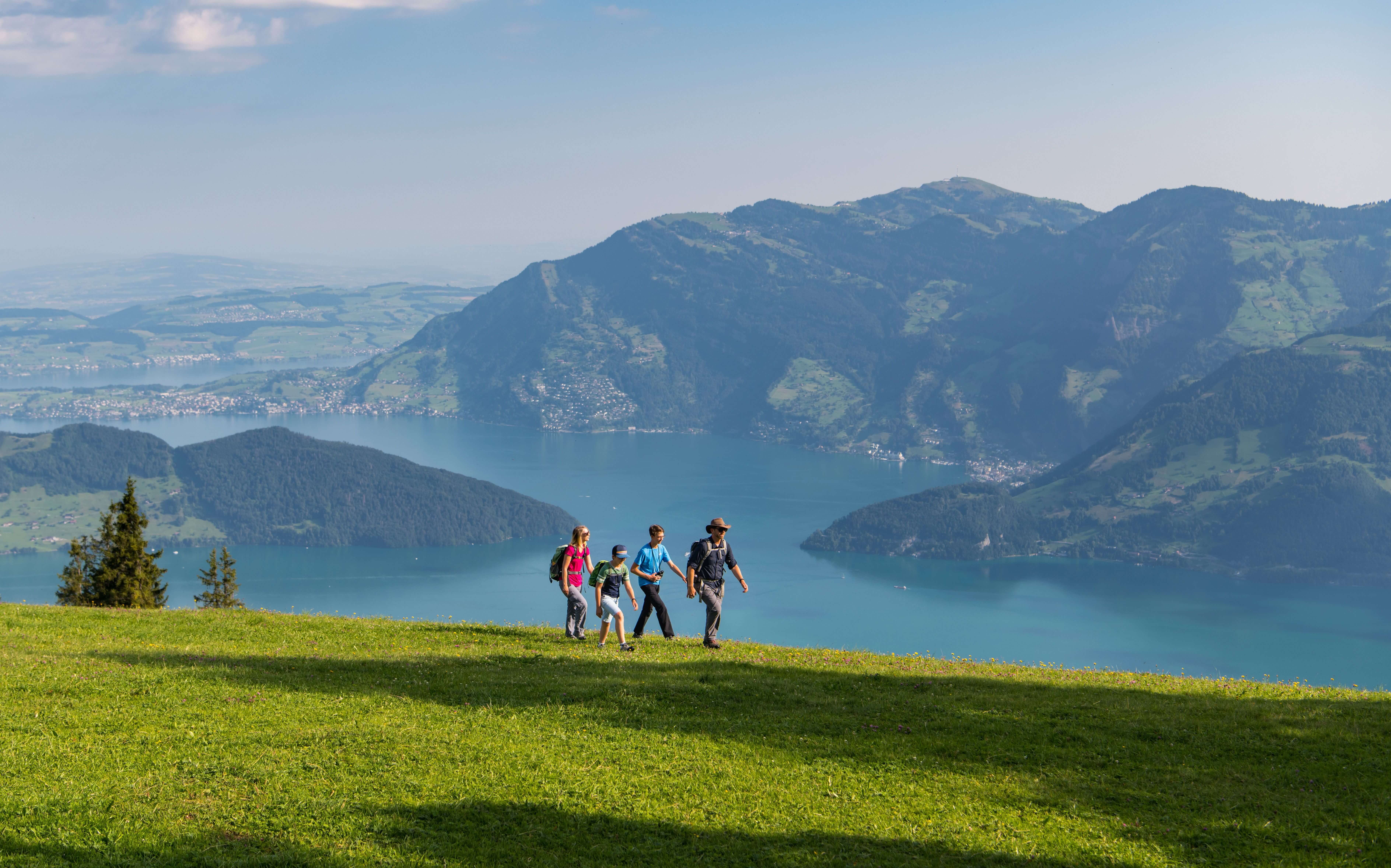 Familie am Wandern im Gebiet Klewenalp-Stockhütt, im Hintergrund das Panorama über den Vierwaldstättersee und die umliegenden Berge